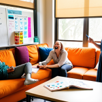 **

A diverse group of teachers are laughing and collaborating in a brightly lit lounge area. Some are gathered around a table covered in lesson plans and colorful markers, while others are relaxing on comfortable couches with cups of coffee. Sunlight streams through a large window, illuminating a whiteboard covered in inspirational quotes and drawings. The overall mood is supportive, joyful, and collaborative. Focus on the warmth and connection between the teachers.

**